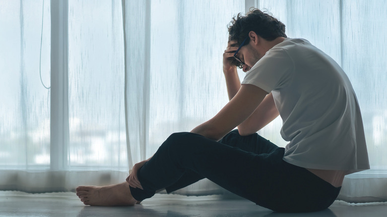 Man sitting on the floor holding his head