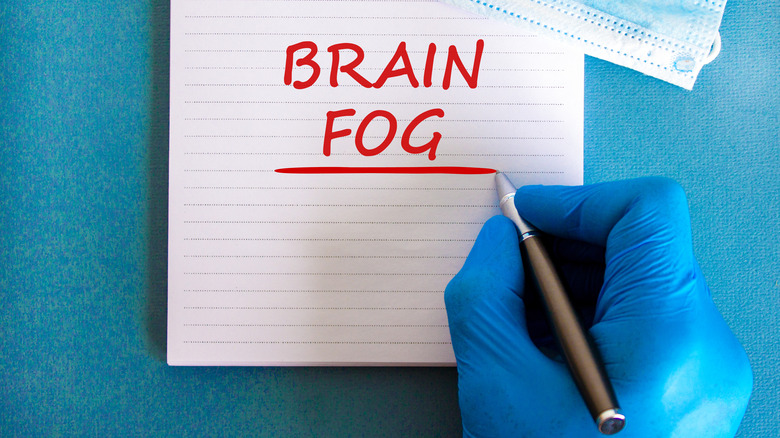 Gloved hand writing "brain fog" in red
