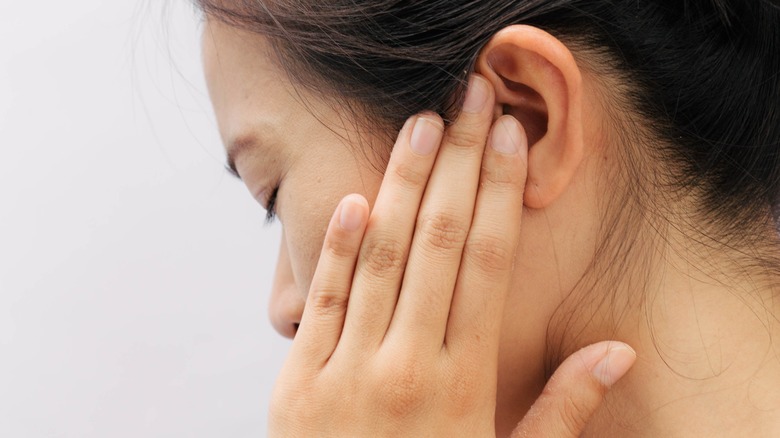 Woman touching her hand to her ear