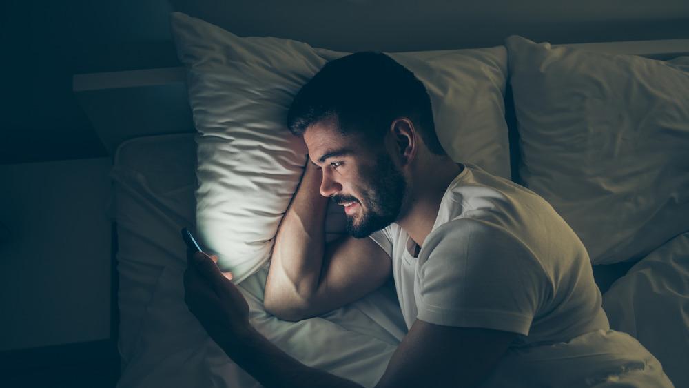 man in bed looking at cell phone