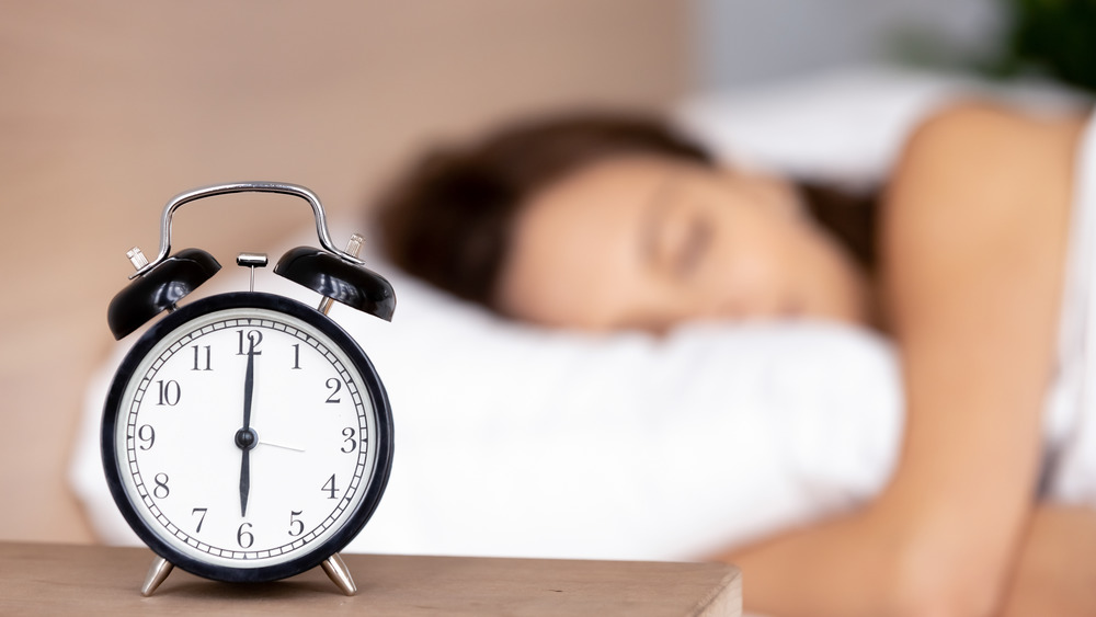 woman sleeping with alarm clock closeby