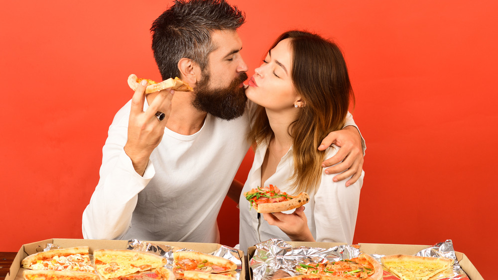 couple kissing while eating pizza