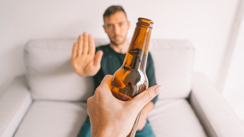 Man on couch refusing alcohol