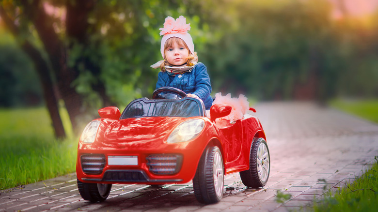 a child driving a red convertible car