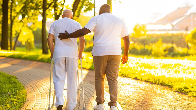 nurse helping older man walk