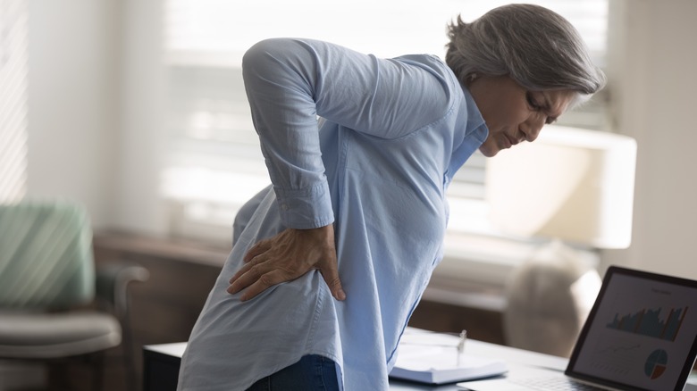 woman bending over holding hip