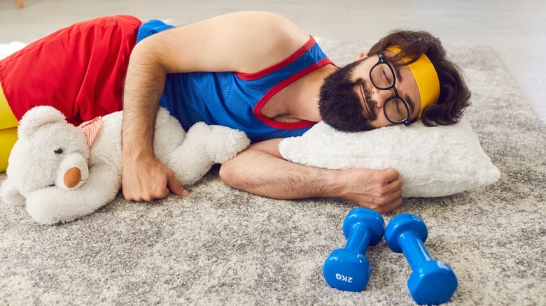 funny sleeping man with weights and teddy bear