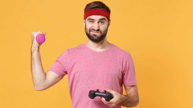 confused man with dumbbell and video game controller