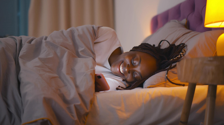 woman checking phone in bed