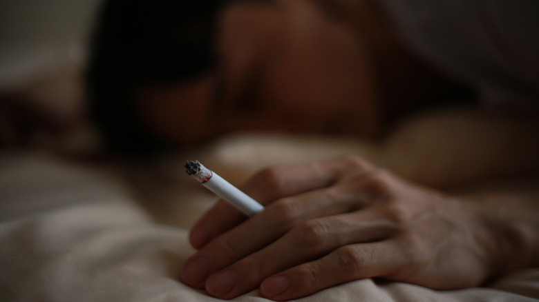 person with cigarette in bed