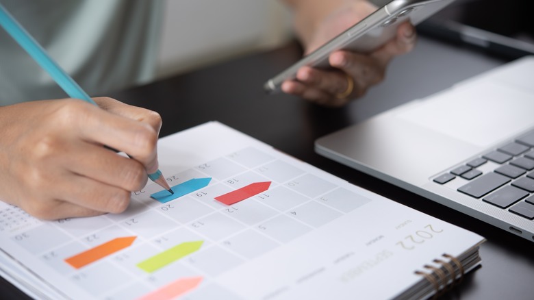 person writes on a calendar