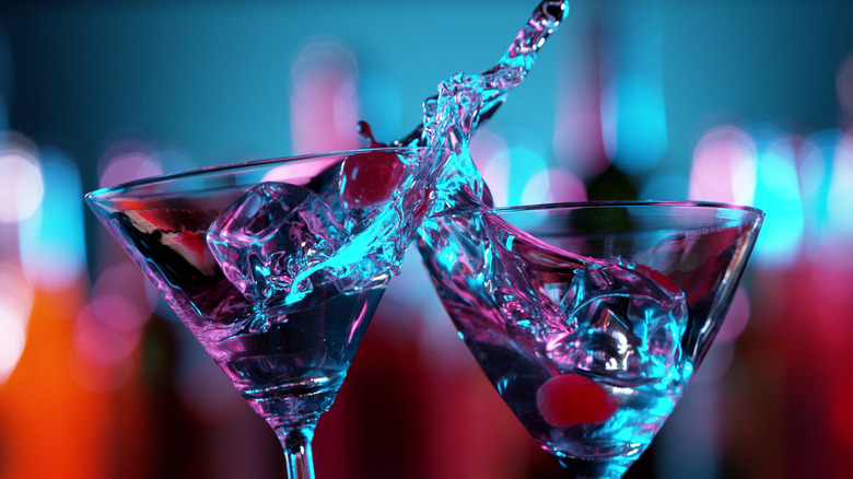 martini glasses toasting against colorful light