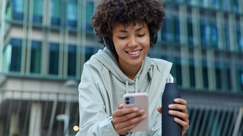 woman drinking water on phone