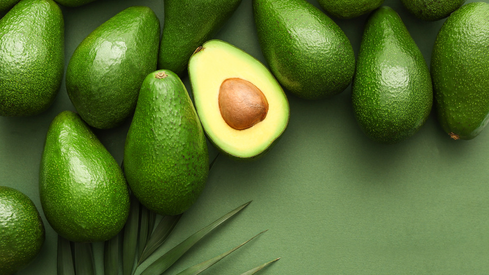 A bunch of avocados against a green background