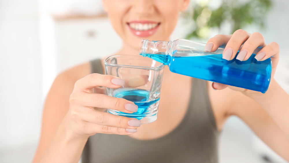 Woman pouring blue mouthwash into a glass
