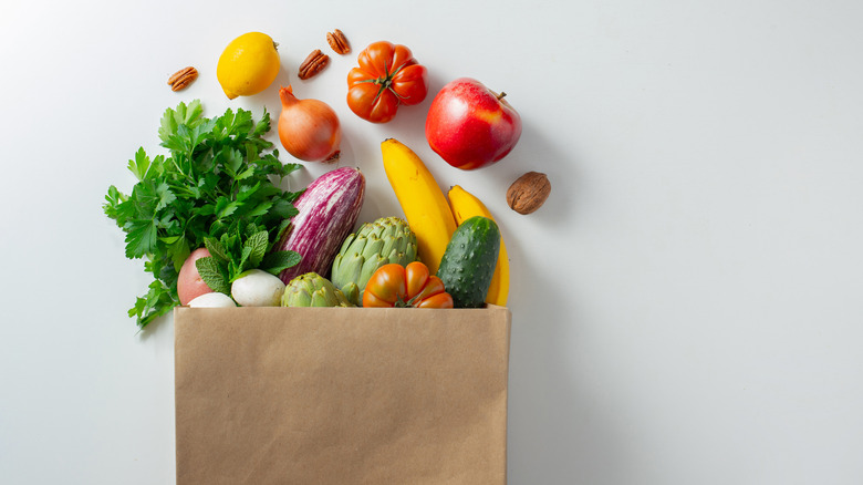 a paper bag of brightly colored fruits and veggies 