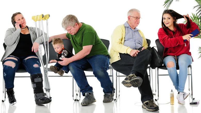 Two adult women, two adult men, and one toddler sitting on chairs in a waiting room 
