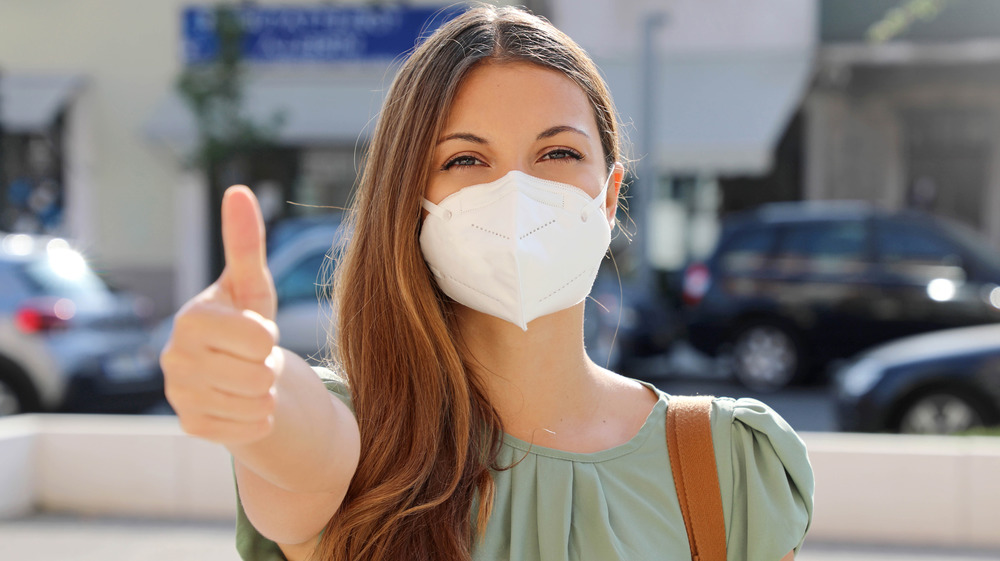 white woman in mask giving a thumbs up