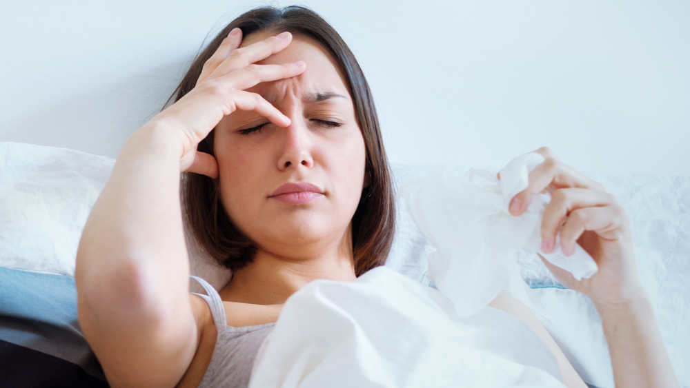 woman holding head not feeling well in bed