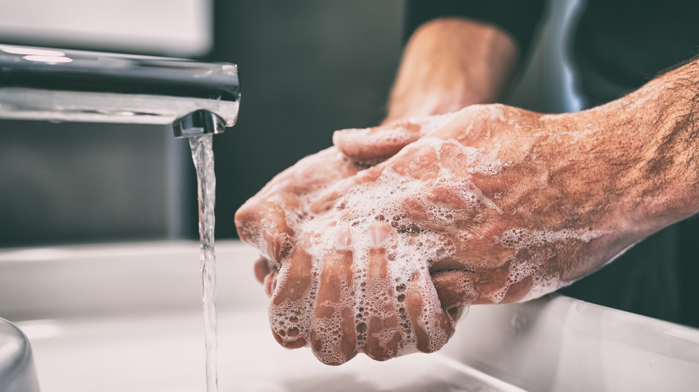 person's hands at sink as they wash them