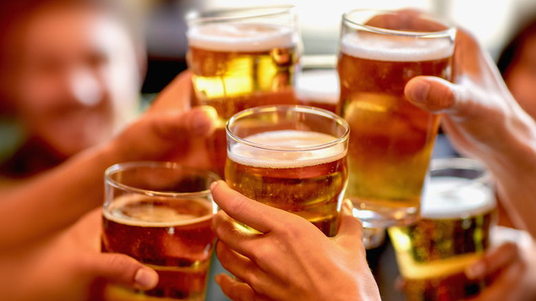 hands holding beer glasses filled with amber beer