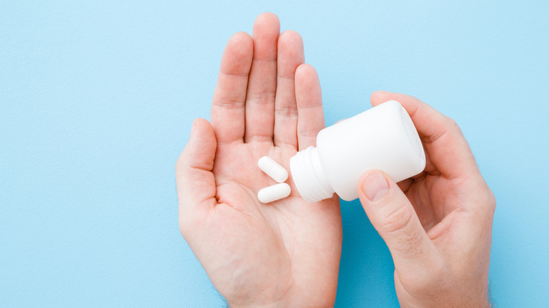 open hand holding pills and a pill bottle