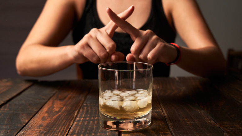 close up of cocktail with woman crossing fingers 