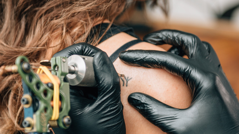 woman getting tattoo on shoulder