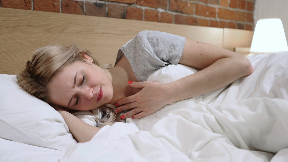 woman in bed holding throat in pain