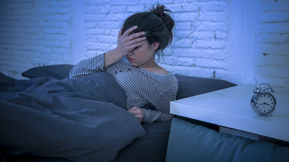 tired woman in bed, hand on head