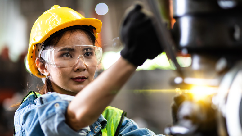 woman wearing safety goggles by machinery