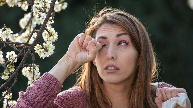 Woman by flowers rubbing her eye