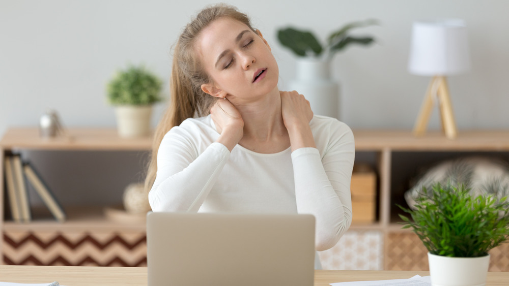 Woman rubbing neck at her desk