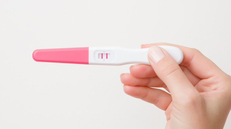 hand holding positive pregnancy test
