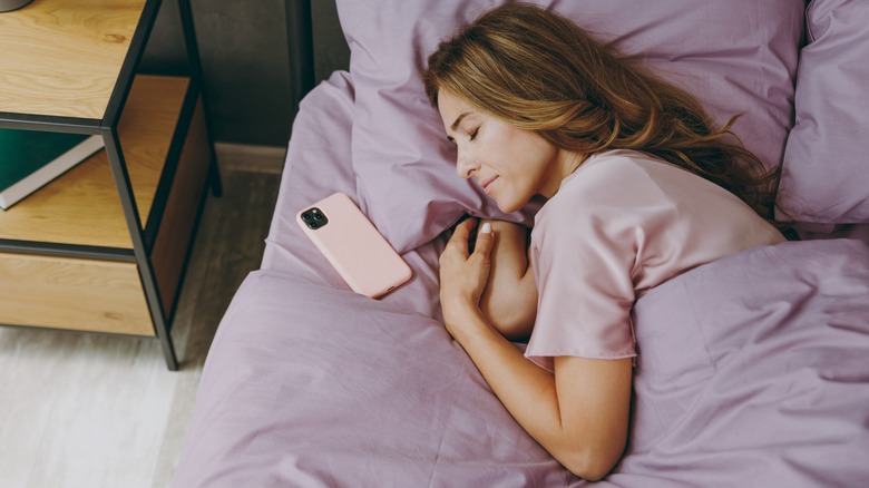 Woman sleeping in bed with phone