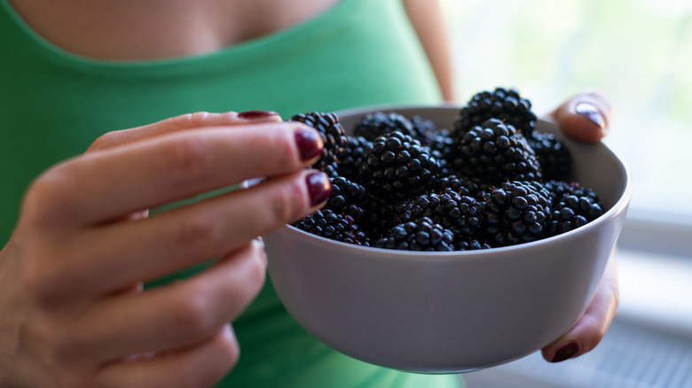 woman holding a bowl of blackberries