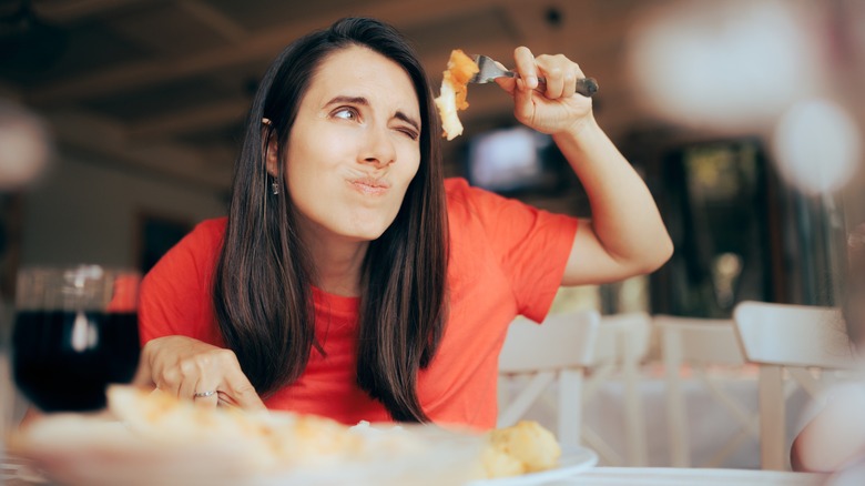 woman overly examining food at a restaurant