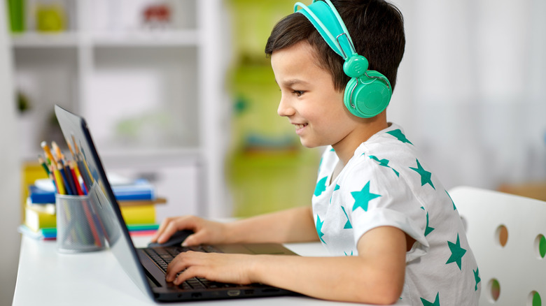 A young boy playing a video game on a laptop