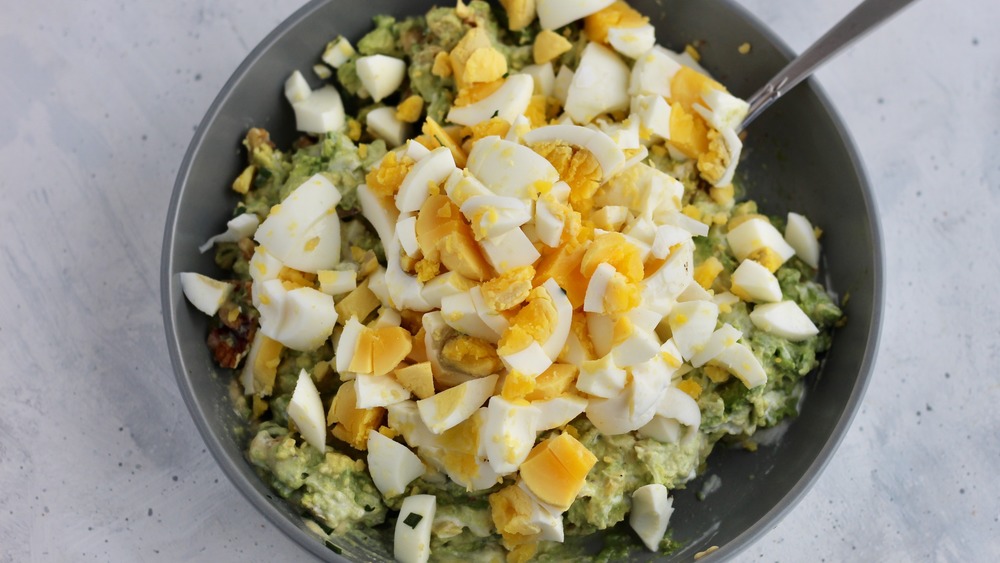 Chopped hard boiled eggs added into healthy egg salad