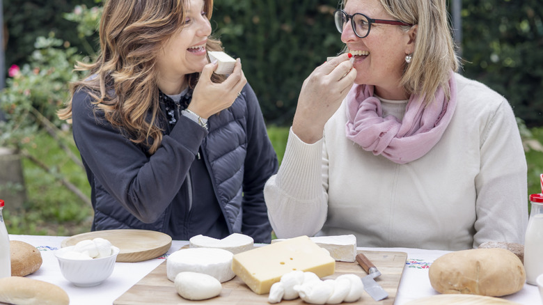 middle age women eating cheese outside at table