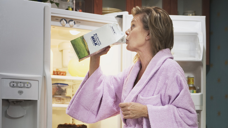 woman drinking milk out of the carton