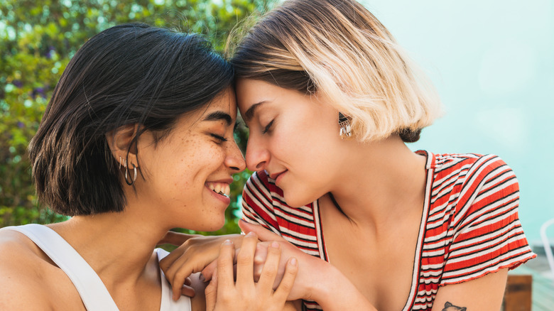 A lesbian couple holding hands and touching foreheads