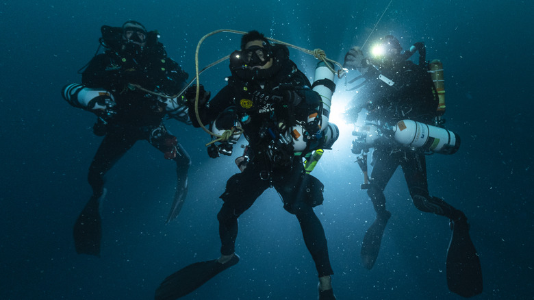 three scuba divers underwater 