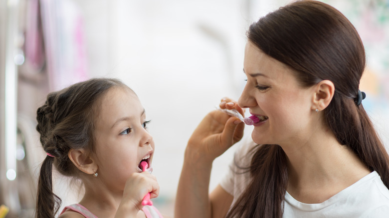 mom teaching daughter brushing teeth