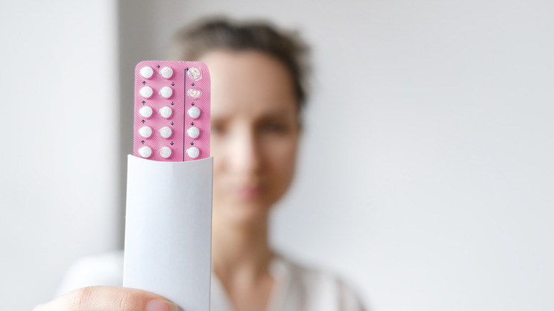 Woman holding birth control pills