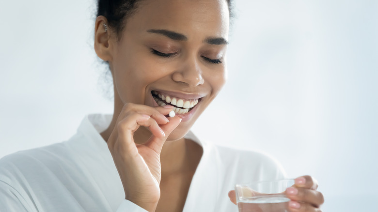 woman taking supplement with water