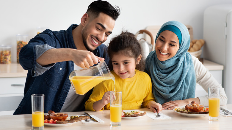 father pouring daughter orange juice