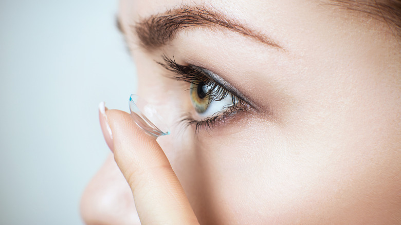 Close up of woman putting contact lens into her eye
