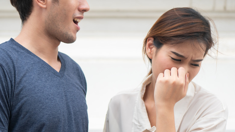 Woman holding nose closed while man breathes out his mouth