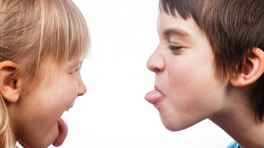 A little boy and girl sticking their tongues out at each other 